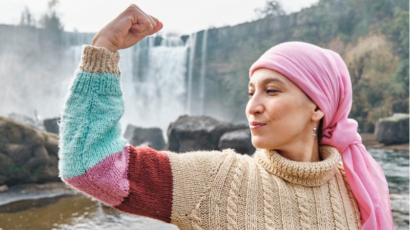 Mulher latina posando em frente a uma cachoeira.