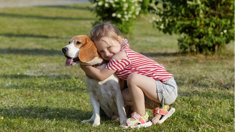 Criança abraçando cão.