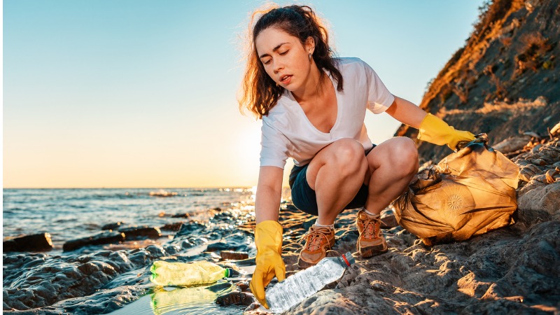 Mulher recolhendo lixo de praia.