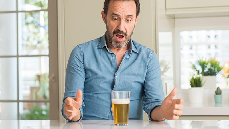 homem surpreso com os riscos de beber álcool