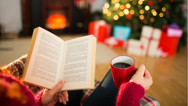 Mulher a ler um livro e tomando café no Natal 