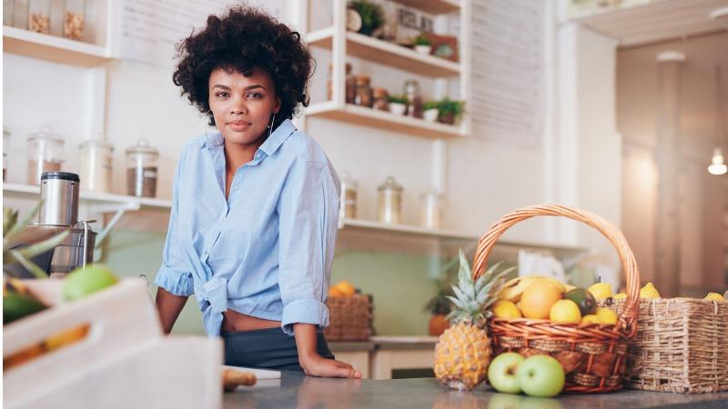 mulher em balcão na cozinha com cesta de vime com frutas em cima de bancada