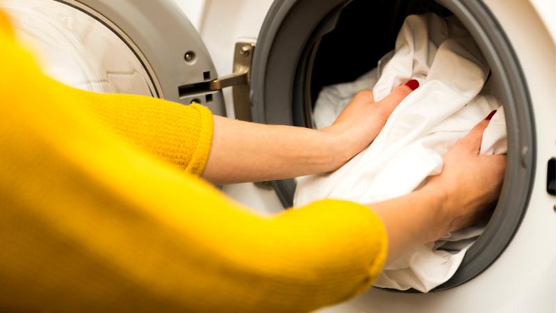 mulher tirando roupa sem manchas da máquina de lavar roupas
