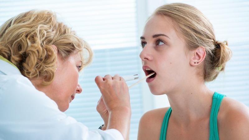 medica examina paciente com dor de garganta
