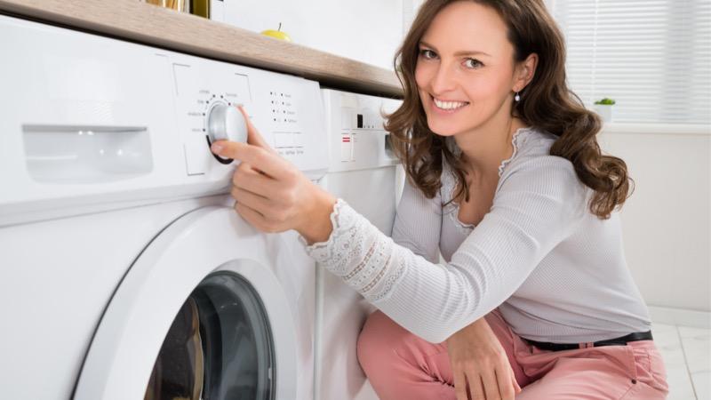 mulher ligando máquina de lavar para tirar mofo