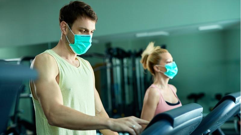 casal se exercitando na academia com mascara de protecao contra o coronavirus covid 19