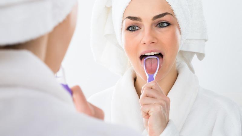 mulher limpando a língua em frente ao espelho