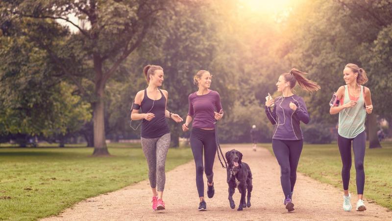 mulher pratigando jogging com amigas e cachorro